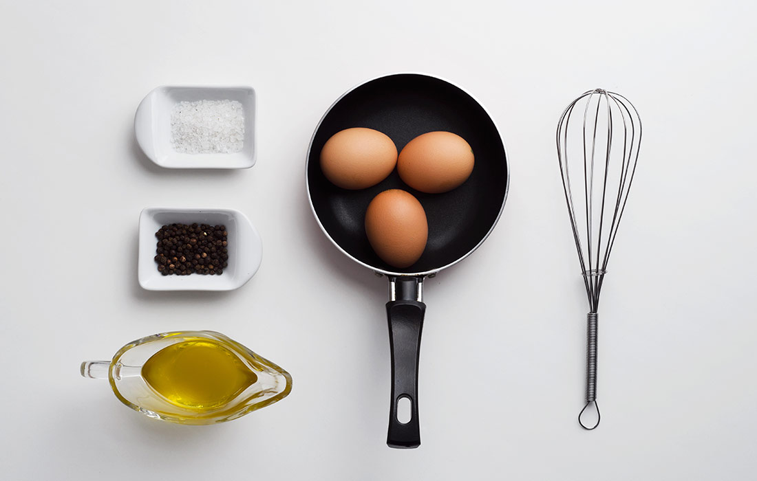 Eggs, spices, oil, whisk, and pan arranged.