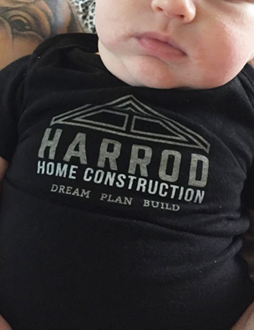 Close-up of a black shirt with 'Harrod Home Construction' logo and slogan.