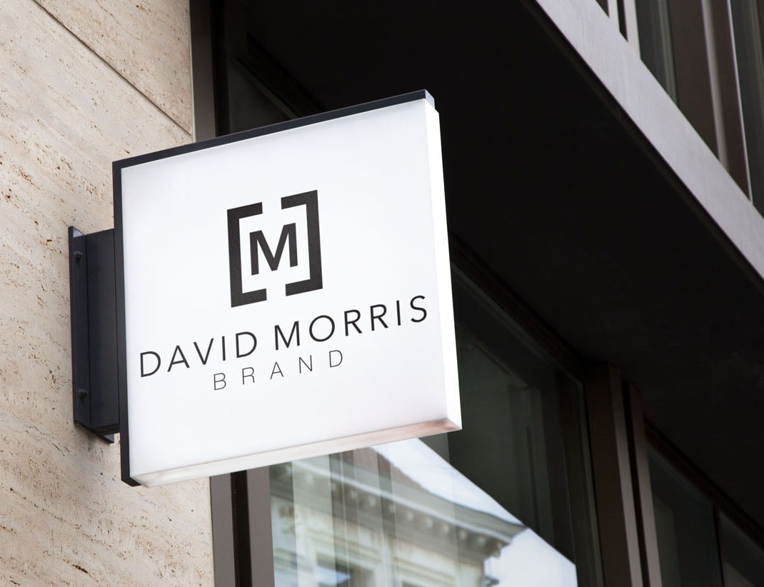 Illuminated sign for David Morris Brand on a building exterior.